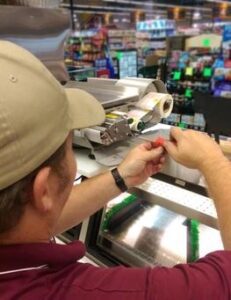 Retail scale repair Technician servicing a commercial scale and label printer in a grocery store