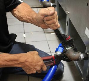 Person fixing pipe with a wrench. Person fixing pipe with a wrench.