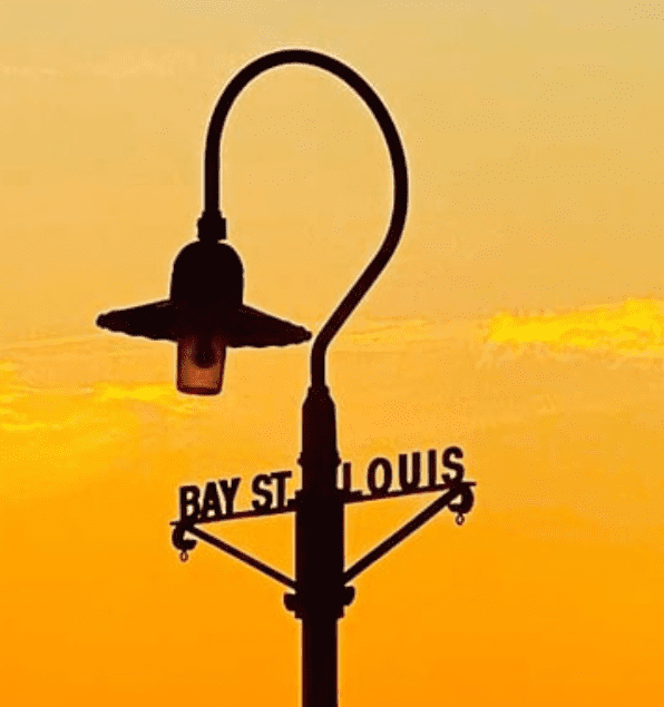 Bay St. Louis street lamp at sunset with pier and orange sky